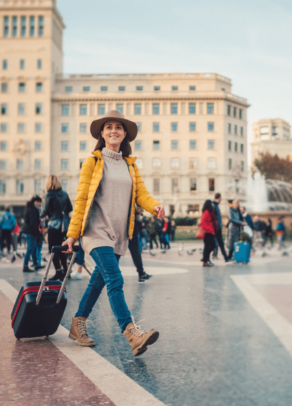 Una mujer pasea tranquilamente con su maleta por Europa ya que se siente protegida por su seguro de viajes